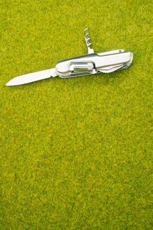 A top view shot of an open steel pocket knife on a green grass surfaceの写真素材