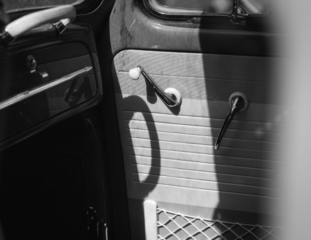 a grayscale shot of the front side door with handles and cases of a vintage classic car from insideの写真素材