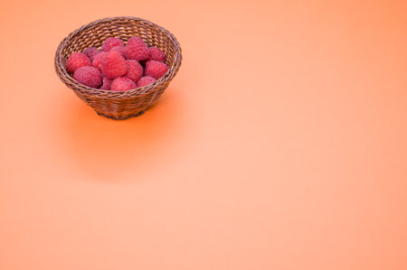 A small basket with fresh raspberries isolated on a light-colored backgroundの写真素材