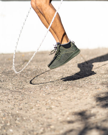 A closeup of a person's legs who is jumping with a skipping rope