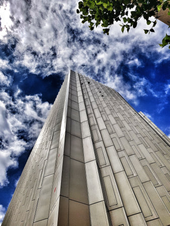 A low angle shot of a beautiful skyscraper under a blue cloudy dramatic sky