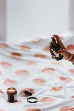 An African female spraying antibacterial sanitizing spray for clothes and linens before going to bedの写真素材