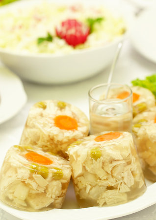 A Polish chicken jelly with an out of focus salad on the tableの写真素材