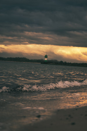 A vertical shot of a wavy sea under a stormy sky at sunsetの写真素材