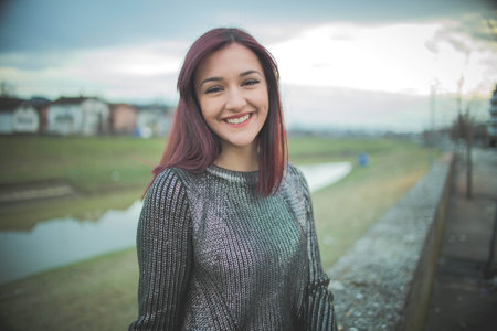 A portrait of a young caucasian female with colored hair smiling in a rural areaの写真素材