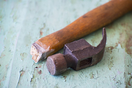 A hammer with a broken handle on a wooden background
