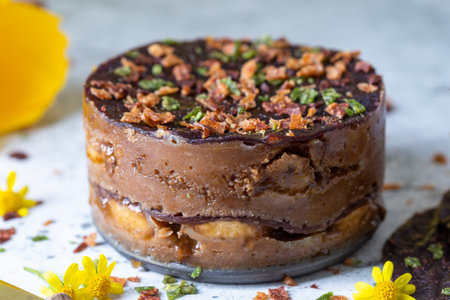 A closeup of a raw cake with bananas and chocolate decorated with flowers on the table