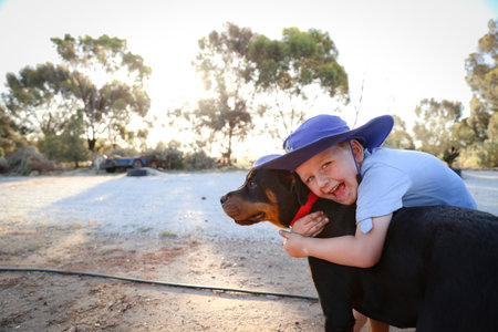 A closeup shot of a white Caucasian kid with blond hair hugging his dogの写真素材