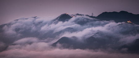 A mesmerizing view of mountain peaks covered by clouds on background of the cityscapeの写真素材