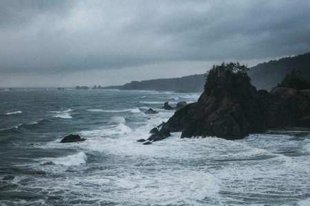 A scenery of foamy ocean waves crashing on the rocky shore on a gloomy dayの写真素材