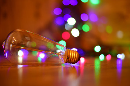A selective focus shot of a lightbulb on the ground with colorful bokeh lights in the backgroundの写真素材