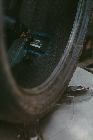 A vertical shot of a car tire missing its rim with a radial patch being applied