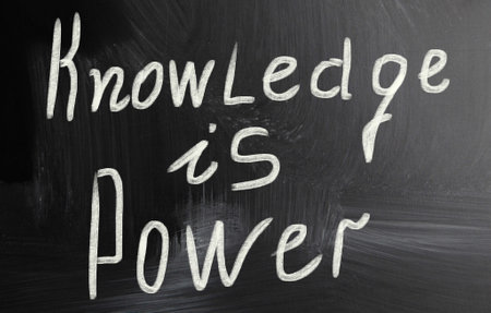 A closeup shot of a white text "Knowledge is Power" on a black surfaceの写真素材