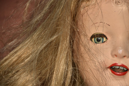A closeup of a creepy old doll face with disheveled hairの写真素材