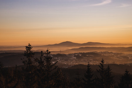 An aerial shot of a landscape with cities and mountains during sunsetの写真素材
