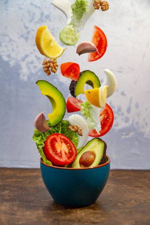 A vertical shot of jumping fruits and vegetables from a blue potの写真素材
