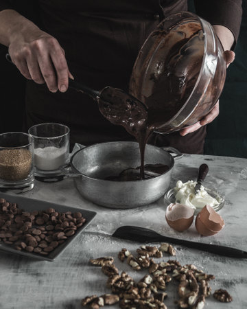 A vertical shot of a person baking brownies with walnuts on the table in the kitchenの写真素材