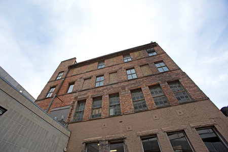 A low angle shot of a brick building against the blue cloudy sky