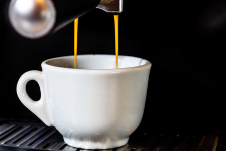 A closeup shot of a cup of hot coffee prepared in a coffee machineの写真素材