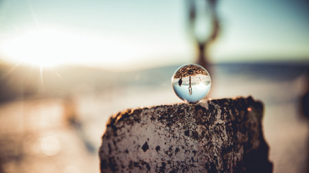 A selective focus shot of a small glass globe on a trunk with a desert in the backgroundの写真素材