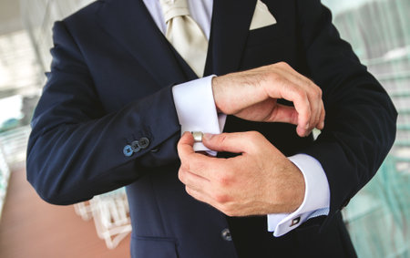 The groom buttoning the sleeves of his shirt getting ready for the weddiの写真素材