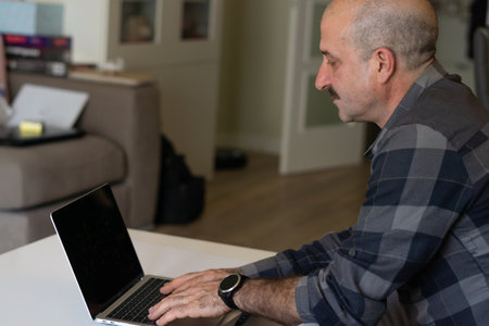 man watching pc and paying online, drinking coffee in the living room of his homeの写真素材