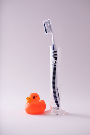 A shot of a blue vertical toothbrush and a duck toy isolated on white backgroundの写真素材