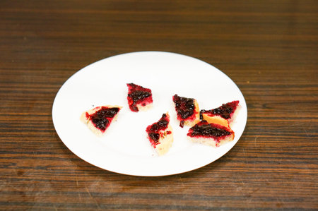 Small bread pieces with berry marmalade on a white plate in soft focus
