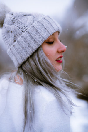 A young Caucasian girl wearing a hat and posing on a snowy dayの写真素材