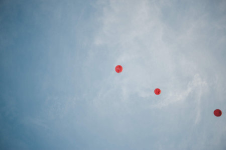 A low angle shot of red gas balloons in the blue sky at daytime - great for wallpapersの写真素材
