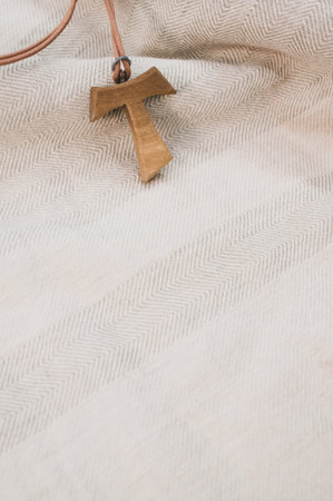 A closeup shot of a wooden tau cross necklace on a wooden background