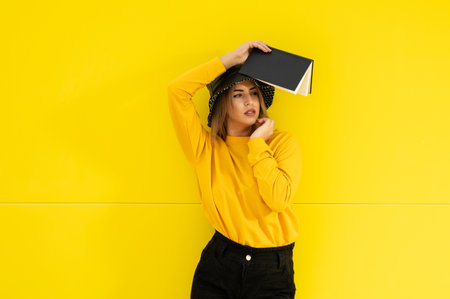 A closeup shot of a young Caucasian lady in yellow with a black book posing for a shotの写真素材