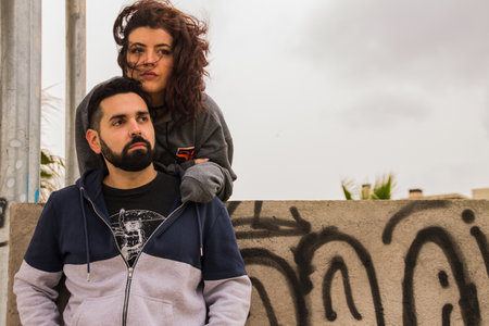 A beautiful Spanish couple in sporty clothes posing on a windy dayの写真素材