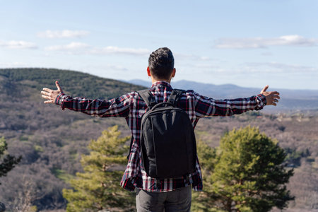 A Spanish man with backpack and open arms enjoying the freedom and the view of mountainsの写真素材