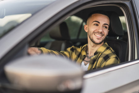 A shallow focus shot of a handsome Spanish Caucasian man sitting behind the wheel of a modern carの写真素材