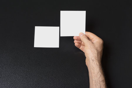 Male hands holding a blank note paper or image frame on dark backgroundの写真素材