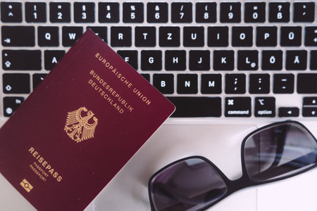 A German passport and sunglasses are on the laptop. Modern way to book vacation and plan the trip.の写真素材