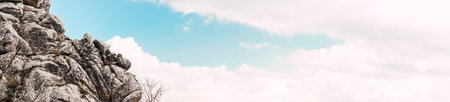 A panoramic shot of a cloudy sky with textured rocks on the left side
