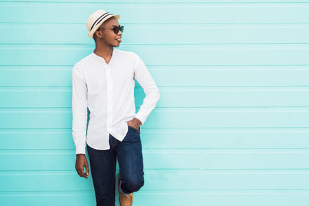 A cool Afro-American male leaning against a light blue background