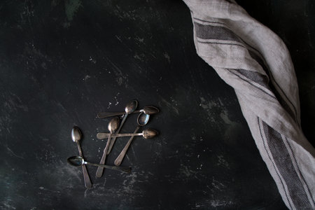 A top view of teaspoons on a dark table by a grey napkin. Free space for your text, copy spaceの写真素材