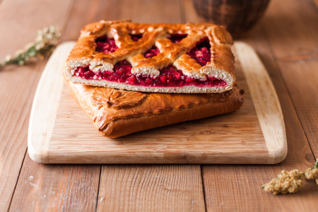 A closeup of appetizing typical Russian stuffed sweet berry pie on a wooden cutting boardの写真素材