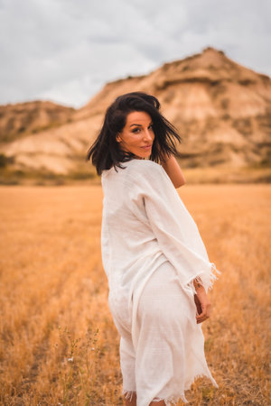 A young brunette Caucasian model in a white dress and a black bikini enjoying in the beautiful desert one summer afternoonの写真素材