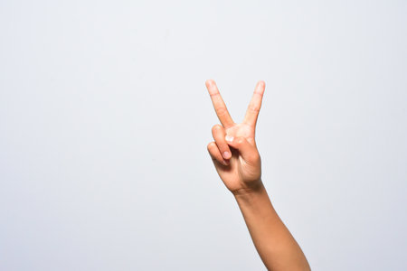 A hand showing the victory symbol isolated on a white backdropの写真素材