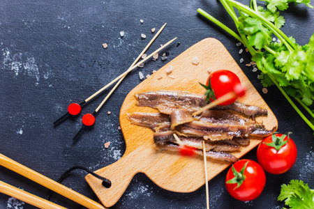 Tasty anchovies, chopsticks, greens, and cherry tomatoes on the dark  backgroundの写真素材