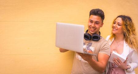 A young entrepreneur couple doing teamwork with a computer against a yellow backgroundの写真素材