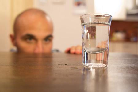 Addicted man looking at a glass filled with alcoholの写真素材