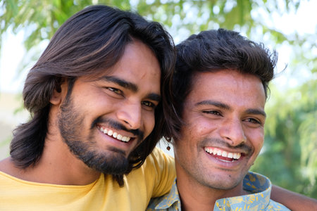 A portrait of a young cheerful Indian gay couple embracing and smiling in a parkの写真素材