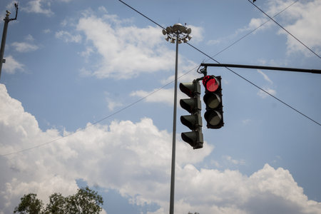 A low-angle shot of the traffic lights showing the red color against the cloudy skyの写真素材