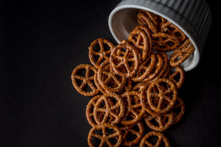 The salty pretzels poured out from the bowl on black backgroundの写真素材