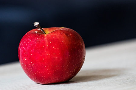 A selective focus of a shiny red ripe apple on blurred backgroundの写真素材